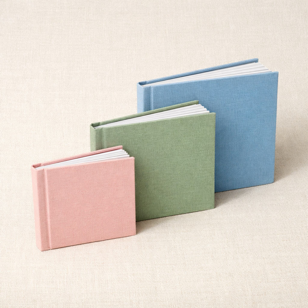 Three photo books in blush, sage, and sky on cream linen